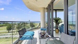A balcony with a clear view of the landscape, a seating area with cushions, and a potted plant.