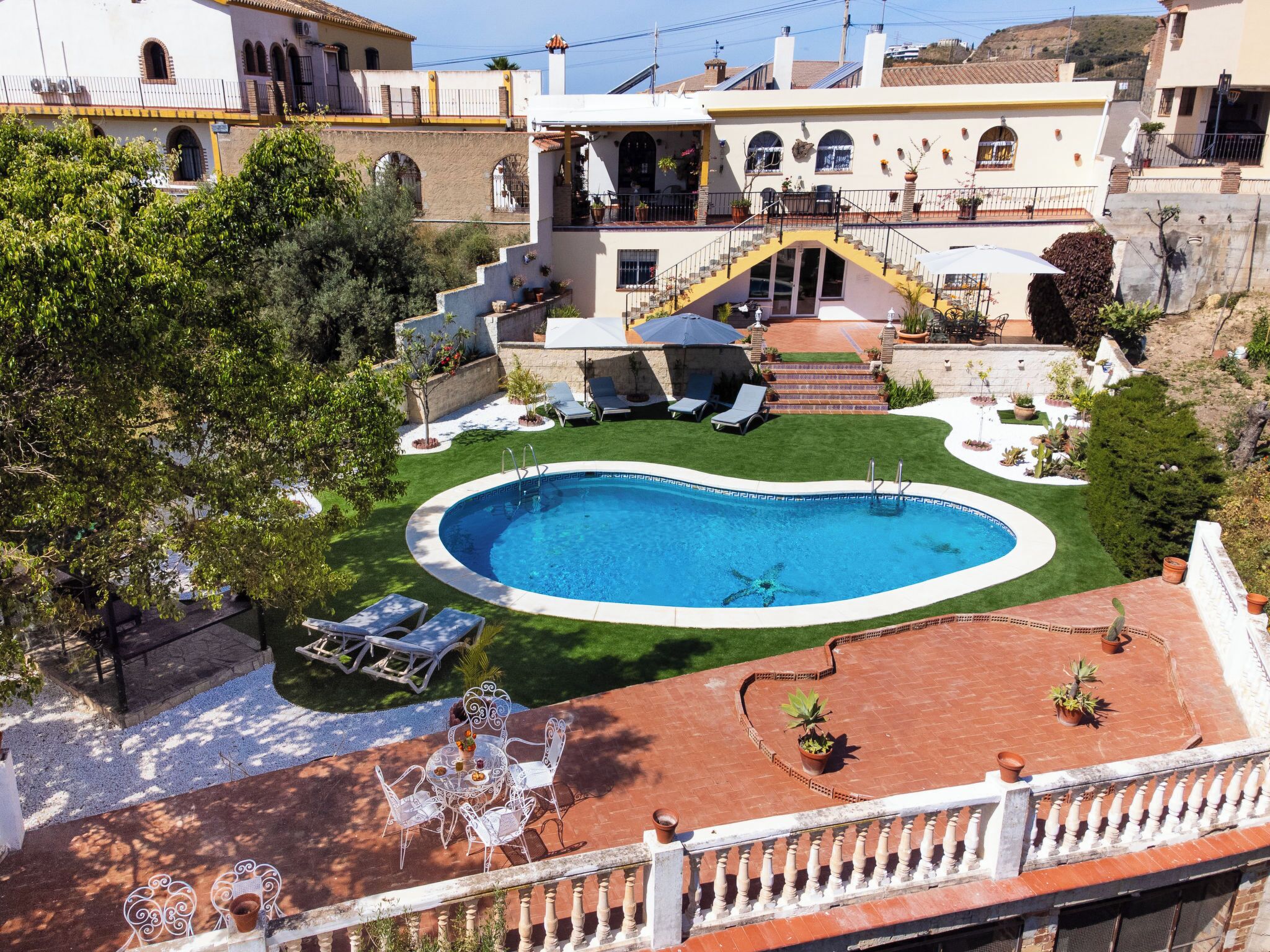 Una propiedad residencial con piscina, zona de estar al aire libre y una escalera que lleva a un balcón.