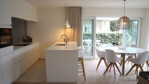 A modern kitchen with a central island, white cabinetry, and a dining area with a round table and chairs.