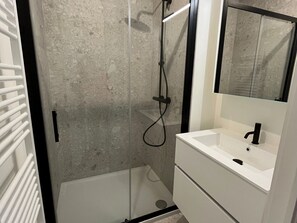 A modern bathroom with a glass-enclosed shower, a white sink, and a mirror above it. - Apartment in Nieuwpoort With sea View (Nieuwpoort)