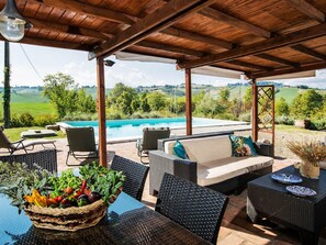 A covered outdoor area with a pool, wicker furniture, and a view of the countryside. - Sunny Holiday Home With Swimming Pool (Salsomaggiore Terme)