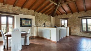 A spacious dining area with a high wooden ceiling, stone walls, and a view of the countryside. - Sunny Holiday Home With Swimming Pool (Salsomaggiore Terme)