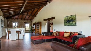 A spacious living area with a high wooden ceiling, a dining table with chairs, a sofa set, and a bookshelf. - Sunny Holiday Home With Swimming Pool (Salsomaggiore Terme)