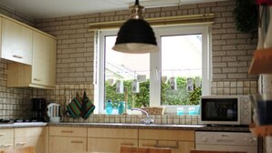 Une cuisine avec des meubles en bois, une fenêtre donnant sur un beau paysage, un four à micro-ondes et un évier.