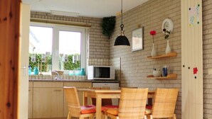 Une cuisine équipée d’une table et de chaises, d’un four à micro-ondes et d’un luminaire suspendu.