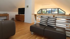 A modern living room with a sofa, a television, and a wooden floor. - Holiday Home Backbert Near Kappeln (Kappeln)