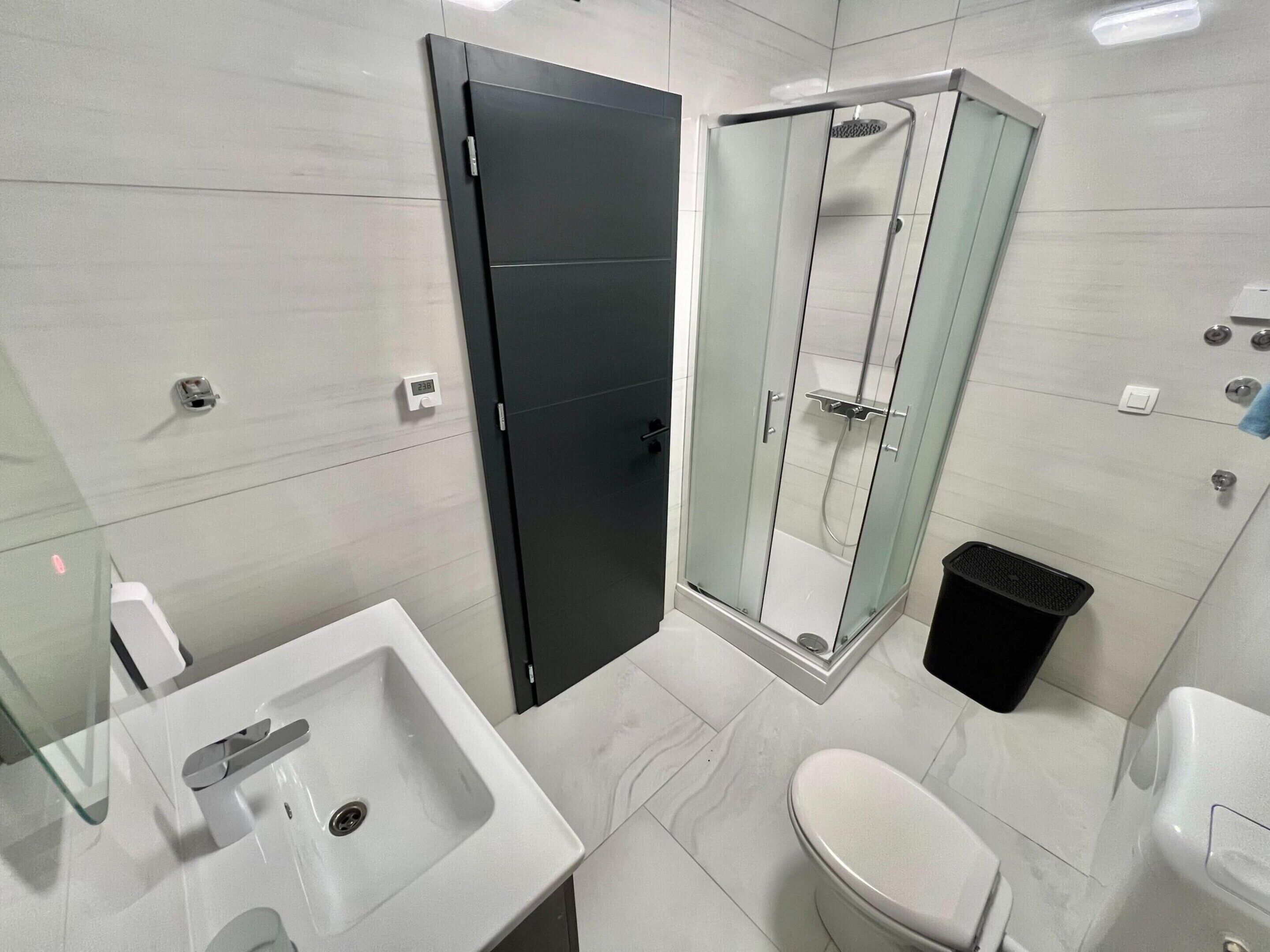 A modern bathroom with a sink, toilet, and glass-enclosed shower.