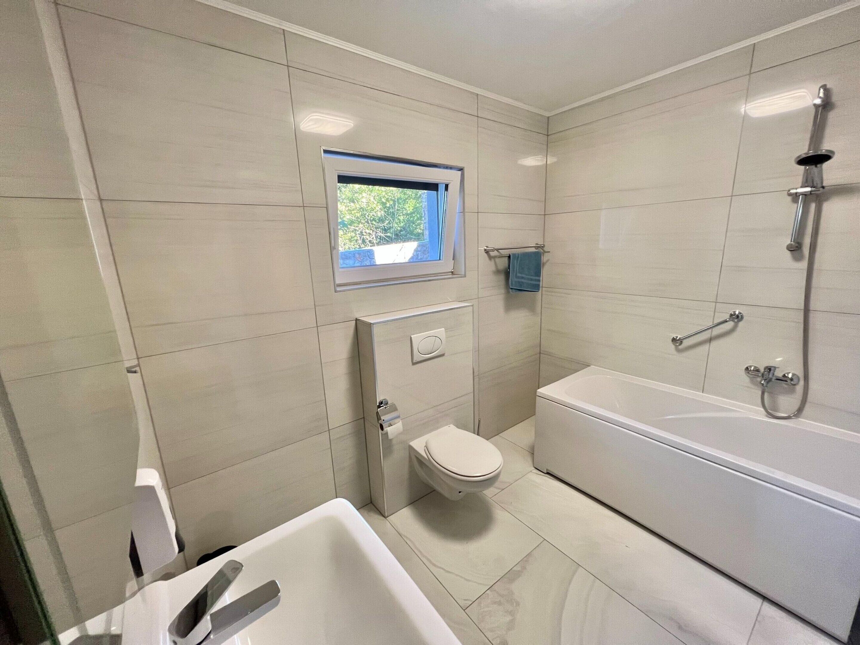 A modern bathroom with a toilet, bathtub, and shower.