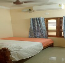 Quarto com uma cama de solteiro, ar-condicionado, janela com persianas de madeira e cortina.