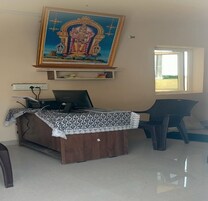 Um quarto com uma escrivaninha de madeira, um computador, uma cadeira e um quadro religioso grande na parede.