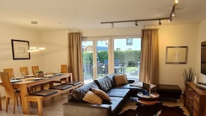 Een moderne woonkamer met een modulaire bank, een eethoek en uitzicht op de omgeving.