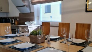 Een eetruimte met een lange tafel voor zes personen, compleet met borden, bestek en wijnglazen.