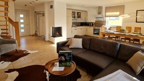Een moderne woonkamer met een bruine leren bank, een houten salontafel en een open haard.