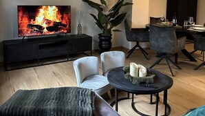 A modern living room with a flat-screen TV, a fireplace, a dining area, and a cozy seating arrangement. - Florentine - Marbi (Varel)