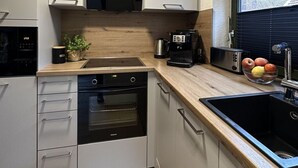 A modern kitchen with a built-in oven, microwave, and coffee maker. - Florentine - Marbi (Varel)