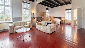 A spacious living room with two sofas, a coffee table, and a large window. - Comfortable Farmhouse With Terrace (Nijeveen)