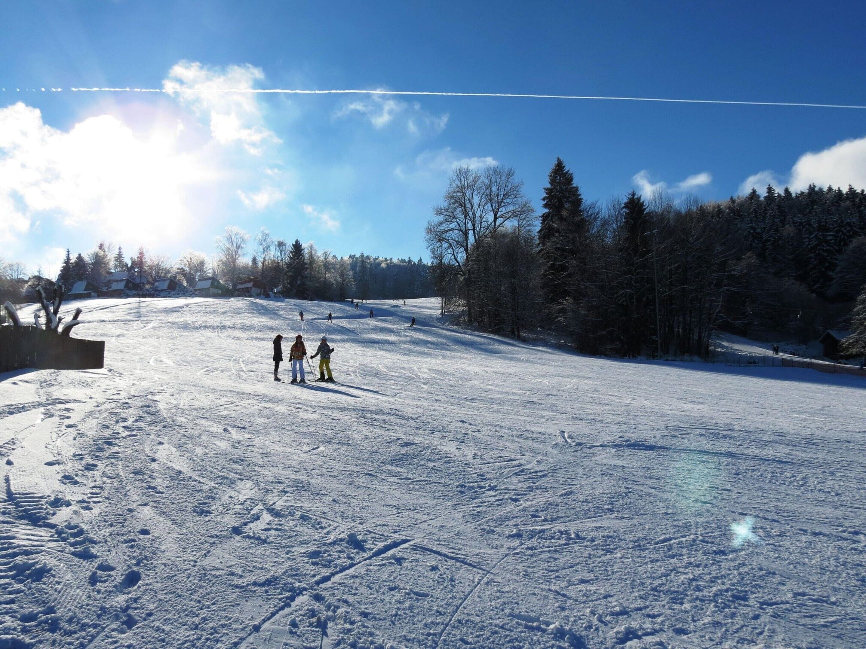 A snowy ski slope with skiers and a clear sky.