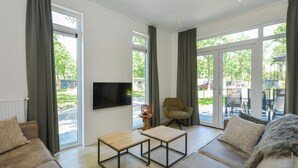 A modern living room with a sofa, armchairs, a coffee table, and a TV mounted on the wall. - Pavilion 6 People With Storage Space (Zorgvlied)