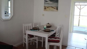 Un comedor con una mesa y sillas blancas, un cuadro en la pared y una ventana con vistas.