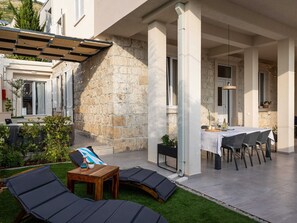 An outdoor patio with lounge chairs, a table, and a dining area with chairs and a table set for a meal. - Apartments Amare - Three Bedroom Apartment With Terrace and Jacuzzi (Dubrovnik)