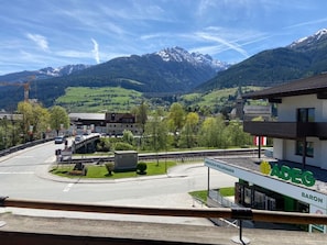 A modern building with a sign reading "ADEG BARON" in a mountainous area with a road and a bridge. - Apartment in Niedernsill Near Ski Slopes (Niedernsill)