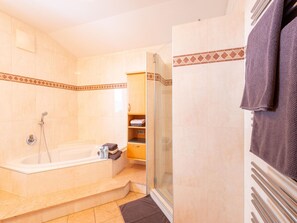 A bathroom with a bathtub, shower, and glass-enclosed shower area. - Apartment in Niedernsill Near Ski Slopes (Niedernsill)