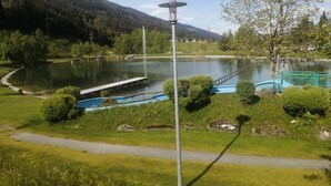 A lakeside view with a dock, a walking path, and a mountain in the background. - Apartment in Niedernsill Near Ski Slopes (Niedernsill)