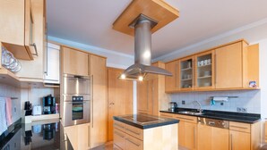 A modern kitchen with wooden cabinets, stainless steel appliances, and a central island. - Apartment in Niedernsill Near Ski Slopes (Niedernsill)