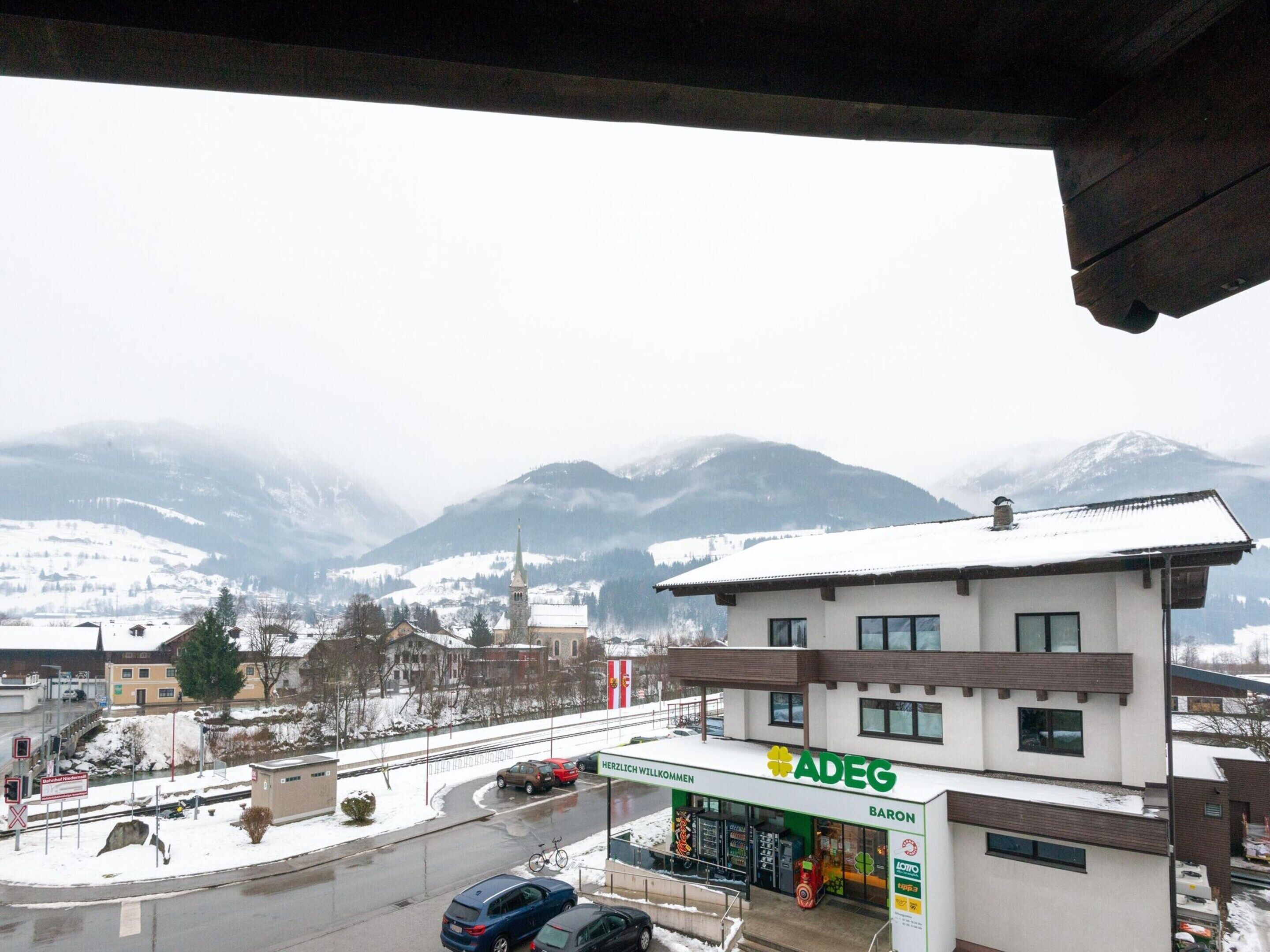 A gas station with a modern design, located in a snowy mountainous area with visible buildings and a clear sky.
