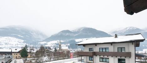 A gas station with a modern design, located in a snowy mountainous area with visible buildings and a clear sky.