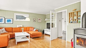 A living room with a sofa, coffee table, fireplace, and a door leading to another room. - 10 Person Holiday Home in Lindesnes (Lindesnes)