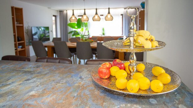 A dining area with a table set for two, featuring a fruit platter and a decorative centerpiece.