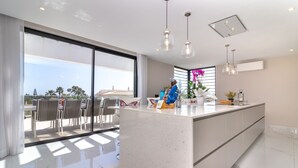 Une cuisine moderne dotée d’un grand îlot central, de grandes fenêtres et offrant une vue sur l’extérieur.