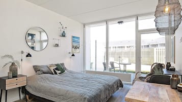 Un dormitorio moderno con una cama grande, una mesa de comedor y un balcón con mobiliario exterior.