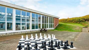 A chessboard set up on a paved area in front of a building with large windows.