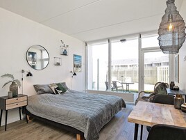 Un dormitorio moderno con una cama grande, una mesa de comedor y un balcón con mobiliario exterior.