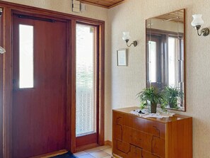 A wooden door with a glass panel, a wooden dresser with drawers, a mirror, and wall-mounted sconces. - 5 Person Holiday Home in Stillingson (Stillingsön)
