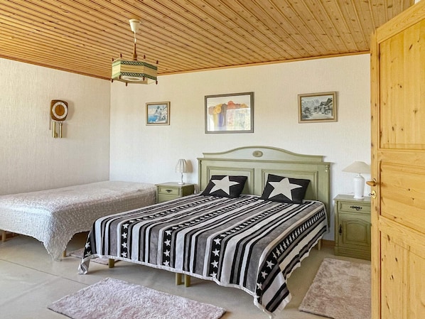 A bedroom with a bed, bedside tables, a wooden ceiling, and wall-mounted pictures. - 5 Person Holiday Home in Stillingson (Stillingsön)