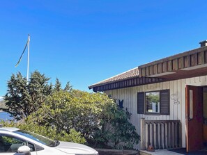 A house with a wooden exterior, a visible chimney, and a car parked in front.