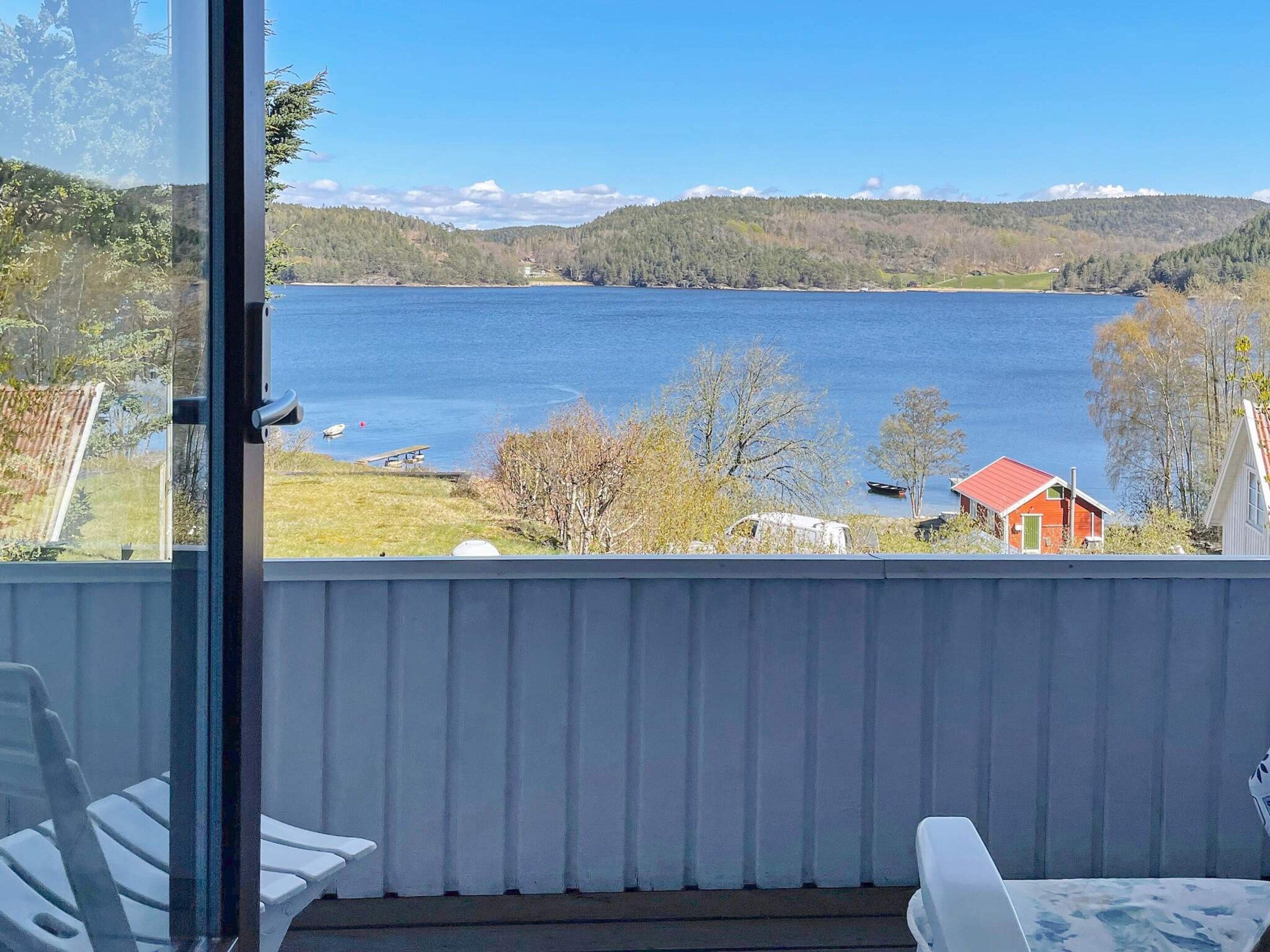Ein Balkon mit Seeblick, ein rotes Gebäude und ein weißes Gebäude.