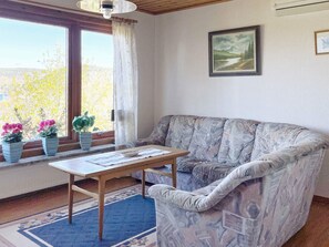 A living room with a sofa, a table, and a window with curtains.