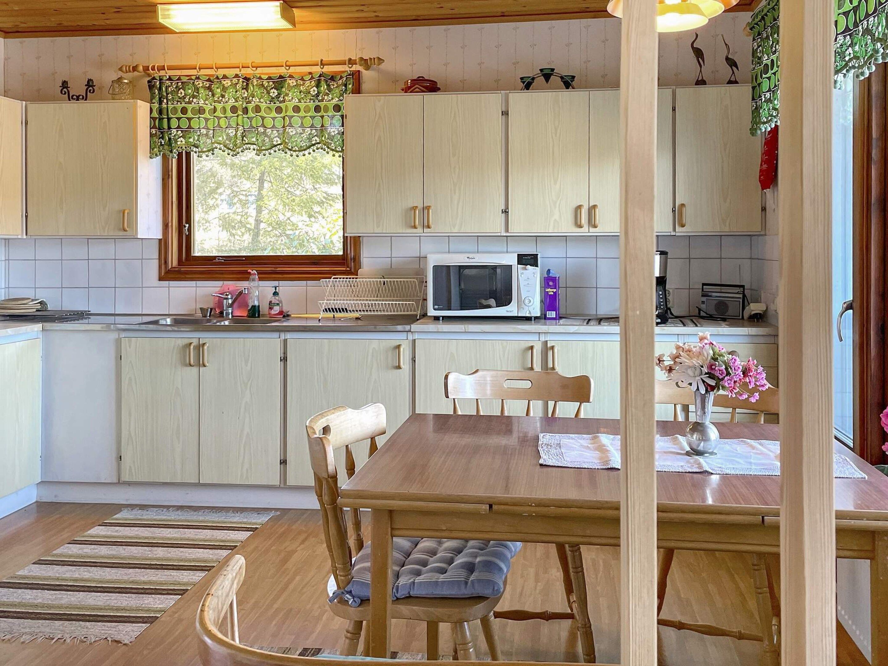 A kitchen with wooden cabinets, a microwave, and a dining table with chairs.