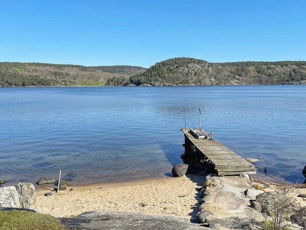 A wooden pier extending into a calm lake with a forested hill in the background.