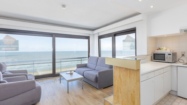 Een moderne woonkamer met een bank, salontafel en uitzicht op zee.