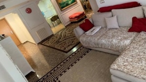 A living room with a sofa, red cushions, a patterned rug, and a painting on the wall. - Belvilla by OYO Apartamento Divendres (Massanassa)