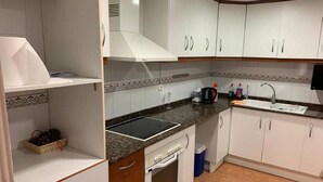 A compact kitchen with white cabinets, a black countertop, a built-in oven, and a sink. - Belvilla by OYO Apartamento Divendres (Massanassa)