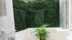 A small balcony with a potted plant, a small table with a blue cloth, and a white wall. - Belvilla by OYO Apartamento Divendres (Massanassa)