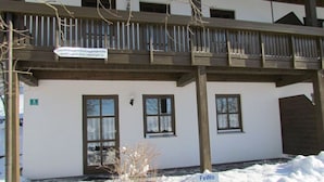 Un immeuble de deux étages doté d’un balcon en bois, d’une enseigne indiquant « FeWo Walter » et du chiffre « 5 » peint sur le mur.