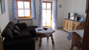 Un salon avec un canapé, une table en bois, un téléviseur et un meuble.