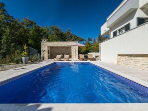 A swimming pool with lounge chairs, a stone structure, and a modern building. - Villa Adrimar Comfortable Holiday Residence (Vrbnik)